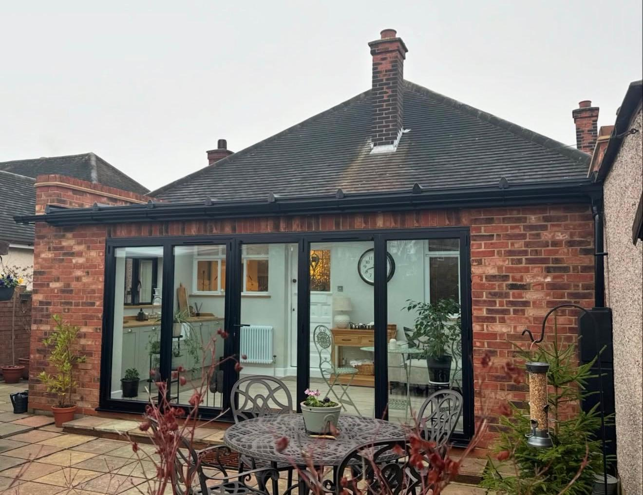 Refurbished rear of bungalow with new brickwork, anthracite bifold doors and pitched tiled roof