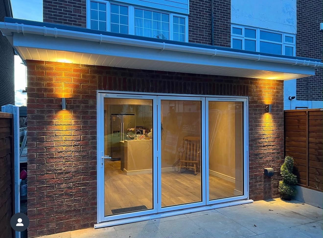 Rear brick extension with bifold doors and exterior uplighters at dusk