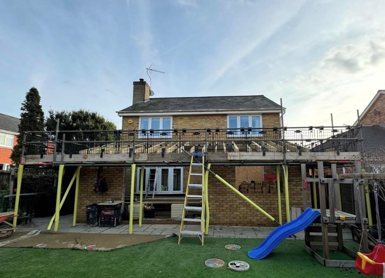 Two-storey rear extension under construction with scaffold and timber joists