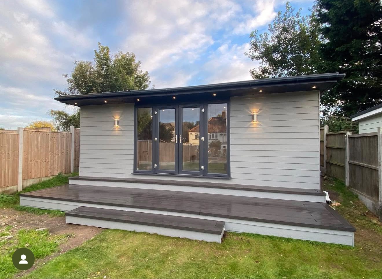 Light grey clad garden studio with stepped composite decking