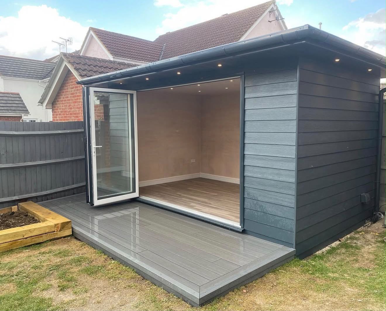 Modern grey composite cladding with open bifold doors on a composite deck