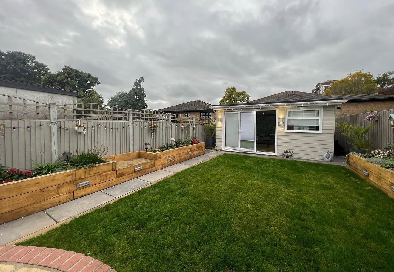 Landscaped rear garden with cream-clad outdoor studio at the end of the lawn