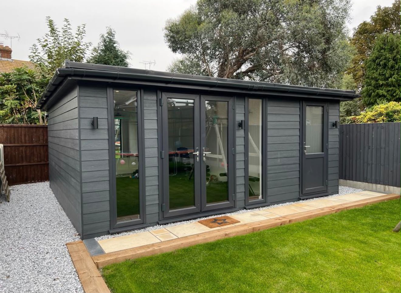 Large dark grey clad outbuilding with multiple French doors and pitched roof
