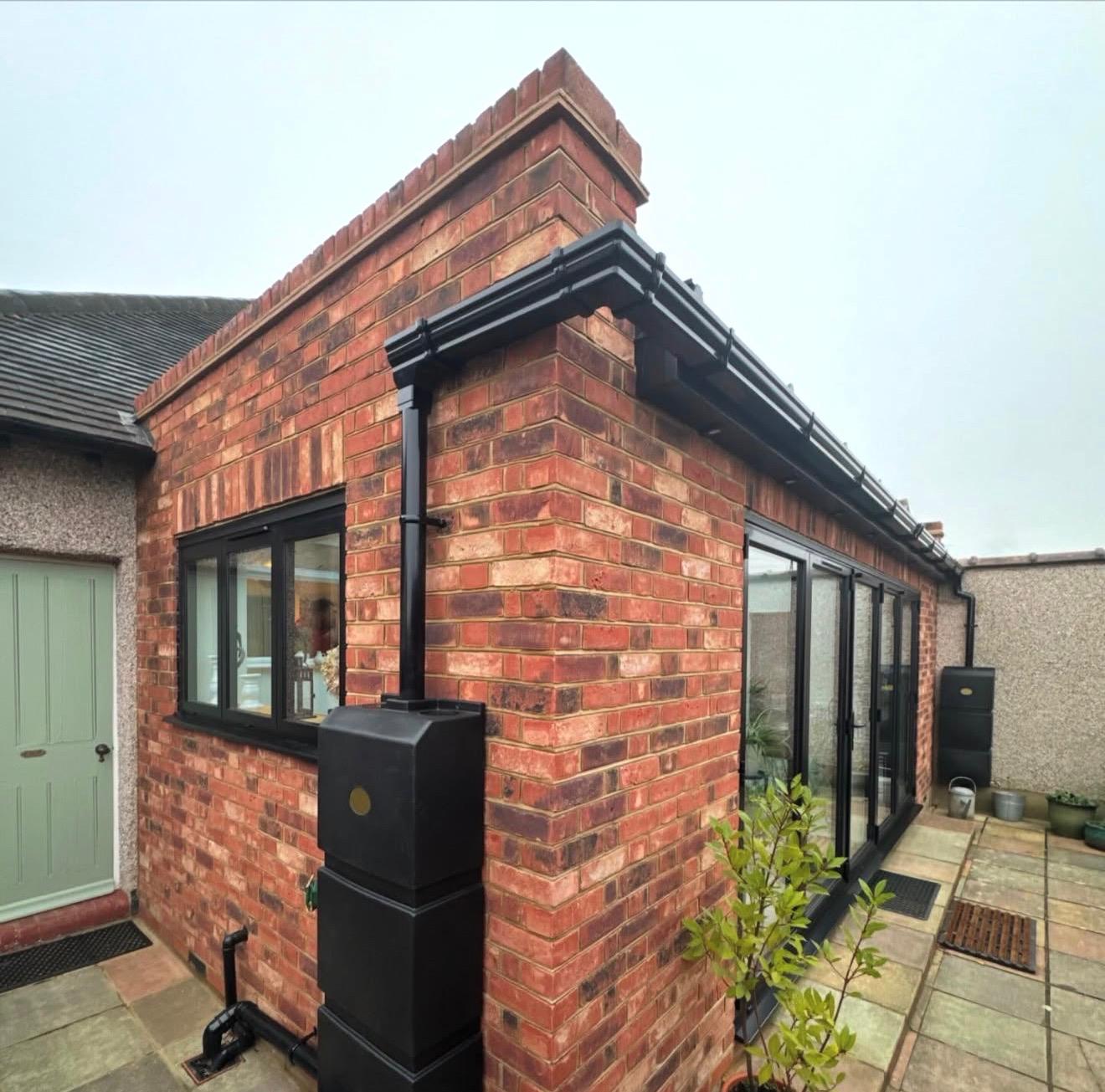 Single-storey red brick rear extension with anthracite guttering and downpipe